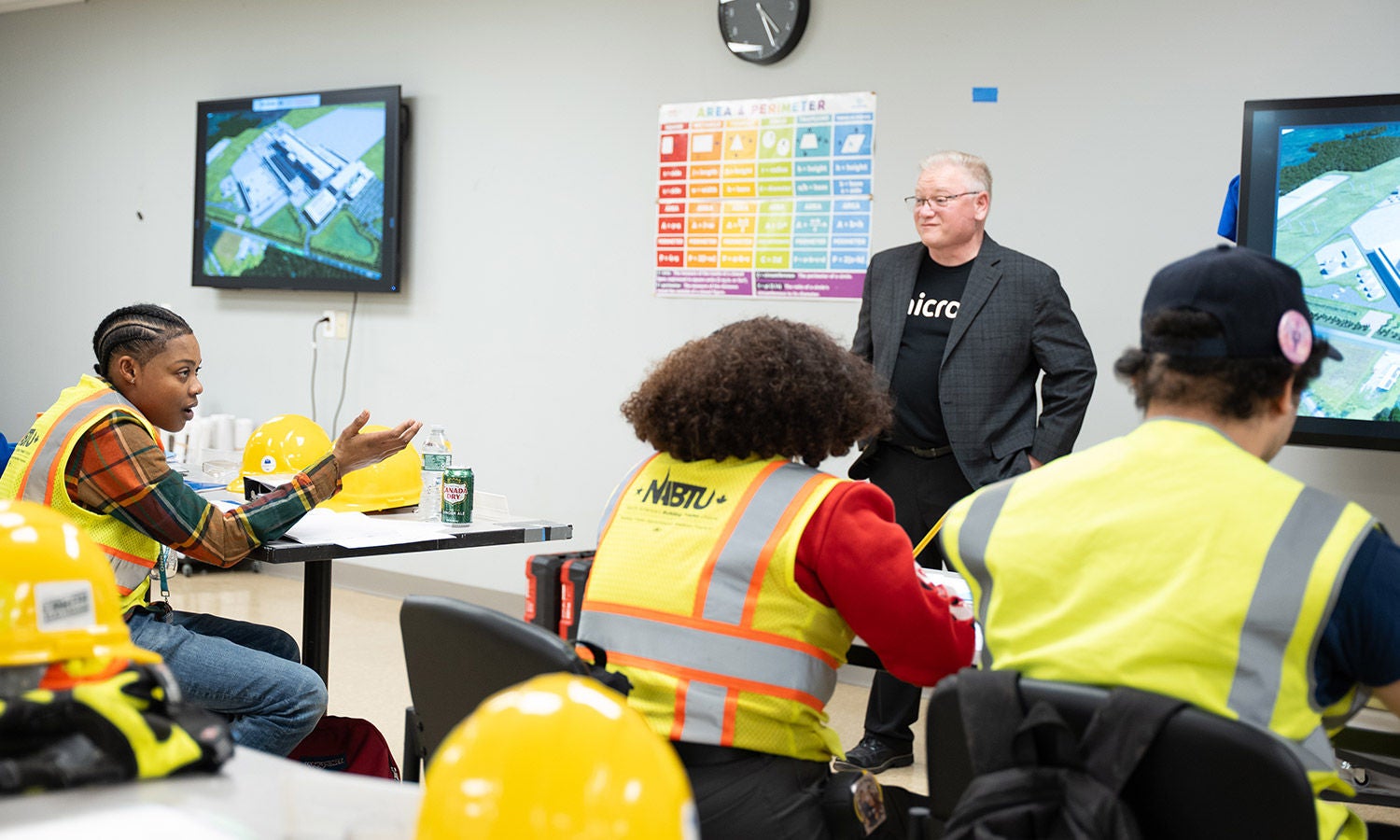 Participants in safety vests and hard hats attending a classroom training session.