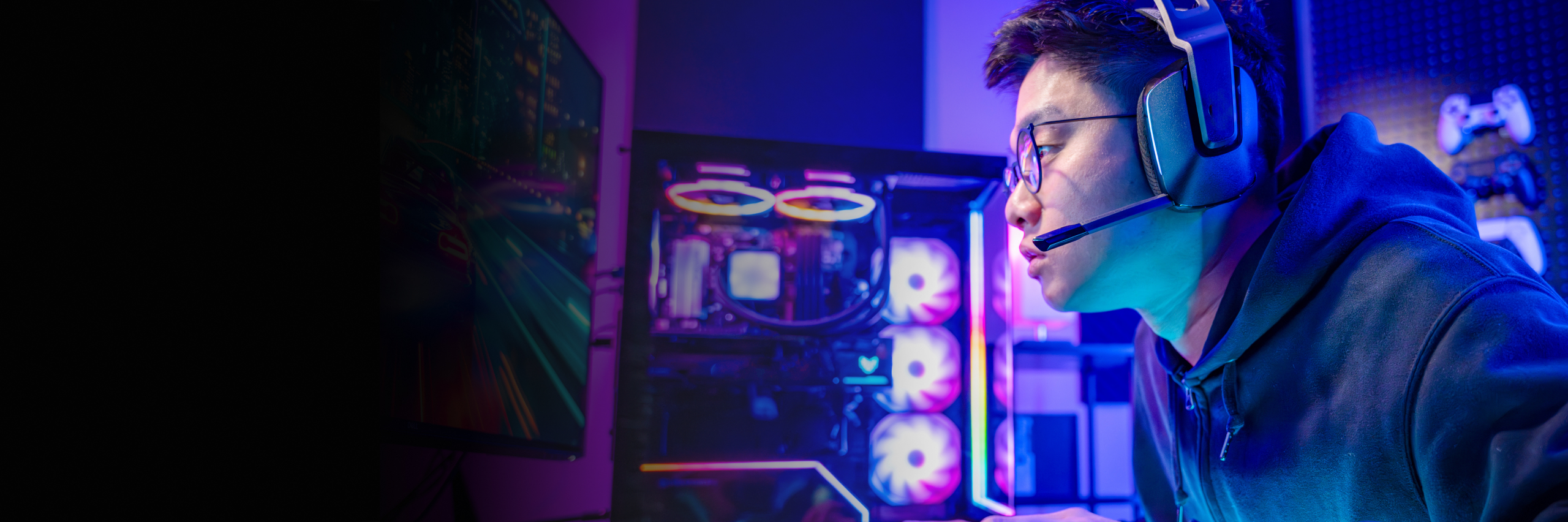 Gamer looking at PC screen with headphones on with blue and purple lights