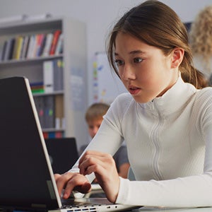 Young students in a classroom environment working on laptop computers