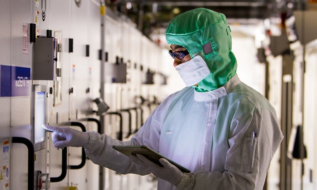 Fabrication plant worker in a clean suit working