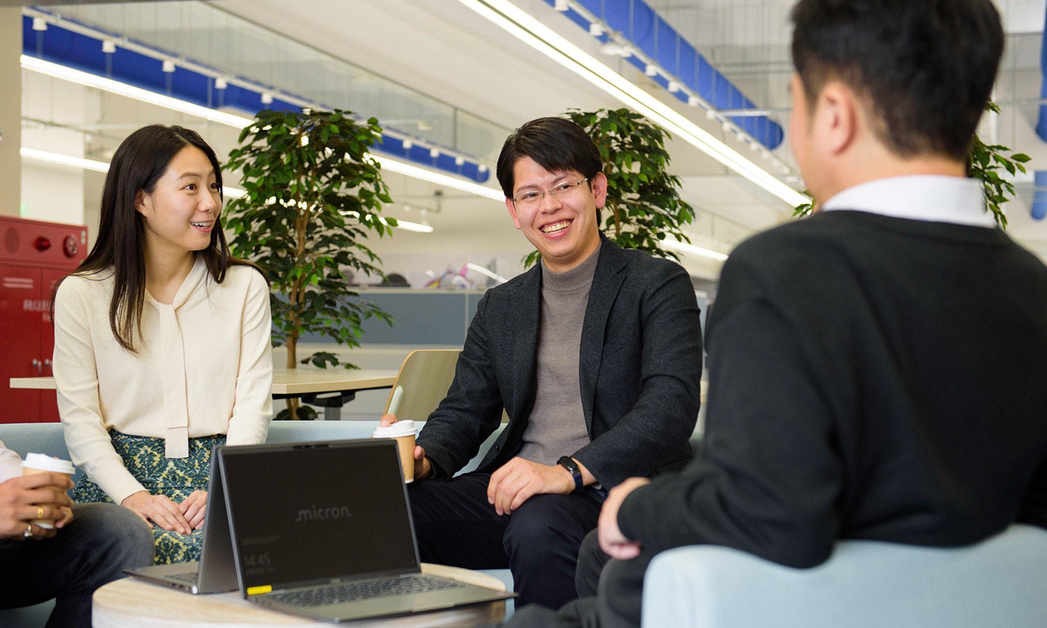 People discussing in a casual office meeting with a laptop.