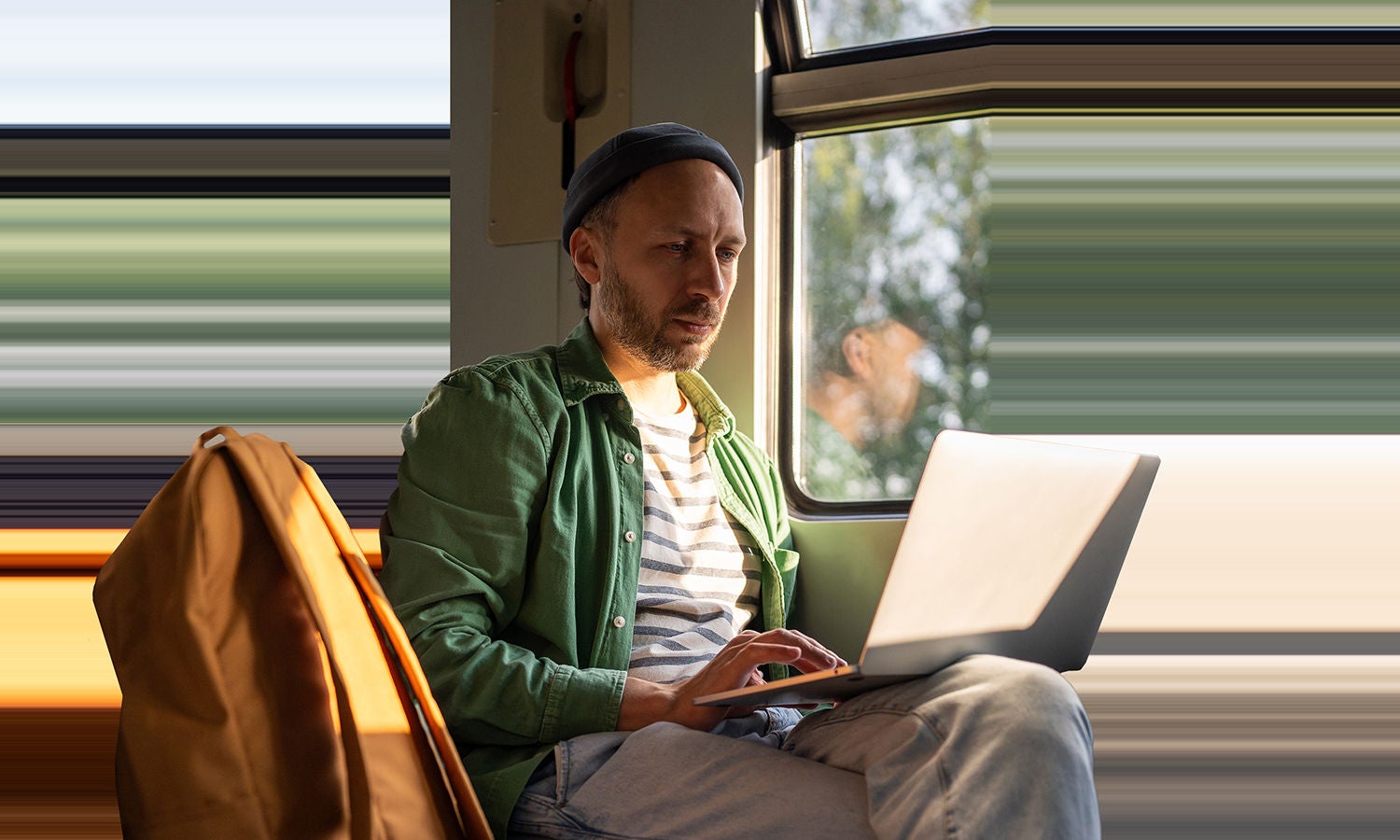 電車の乗客が軽量薄型のPCを使っている。PCの右端がフレームの外へとなめらかに伸びていく。