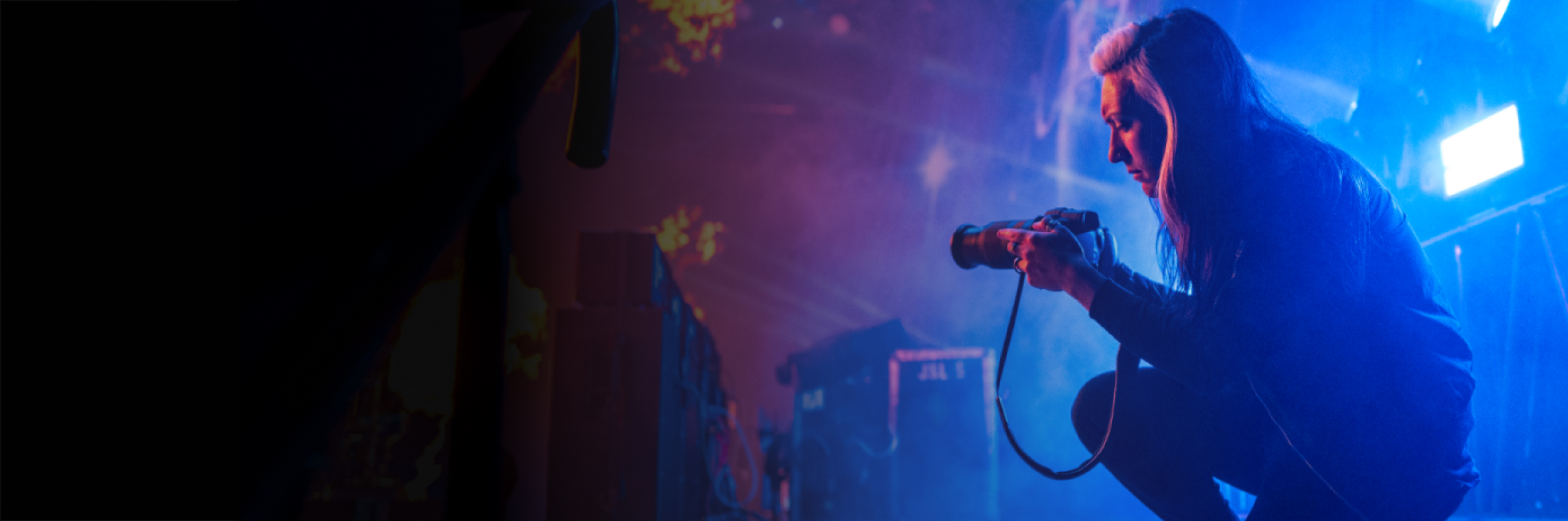 Photographer behind a stage with a camera with blue and purple lighting