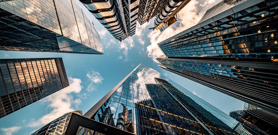 Looking straight up at the sky, through a city of skyscrapers