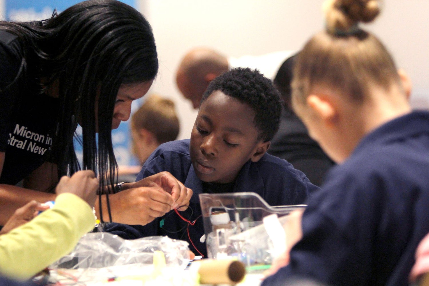 Volunteer helping students with a hands-on STEM activity