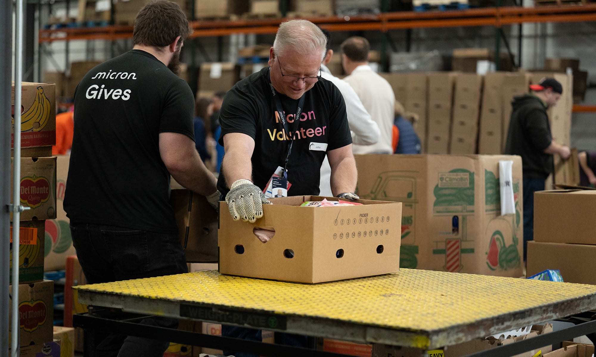Micron volunteers sorting and packing food donations at a community warehouse.