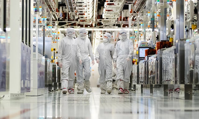 Clearn room employees walking down the hallway of a fabrication plant