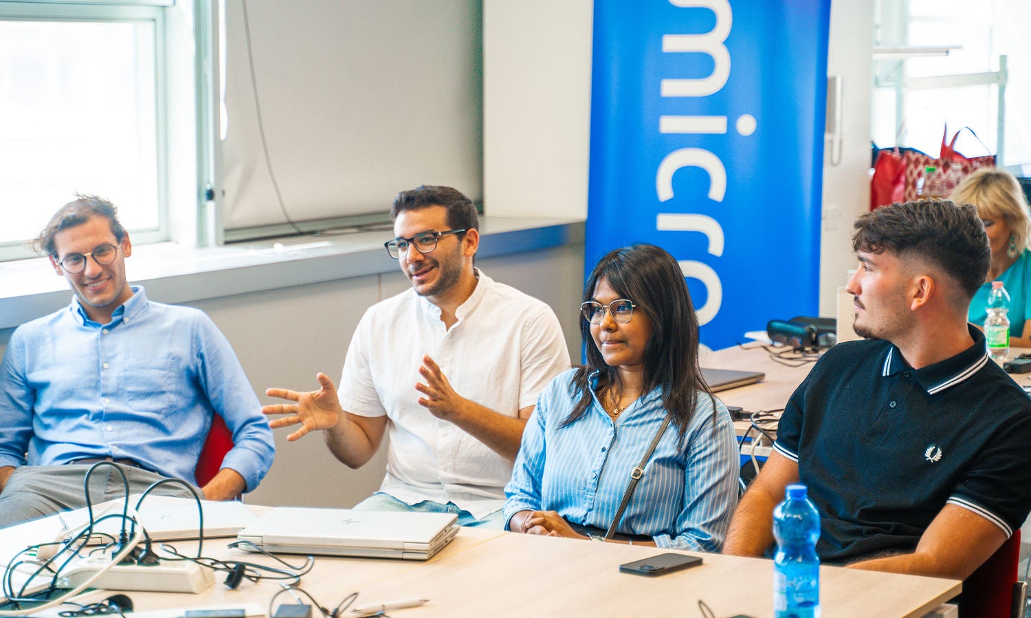 Group of students sitting across the table and micron banner displayed in the background