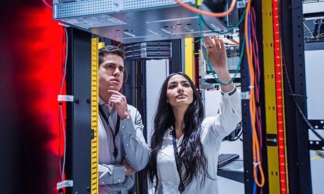 Two co-workers collaborating in a server room