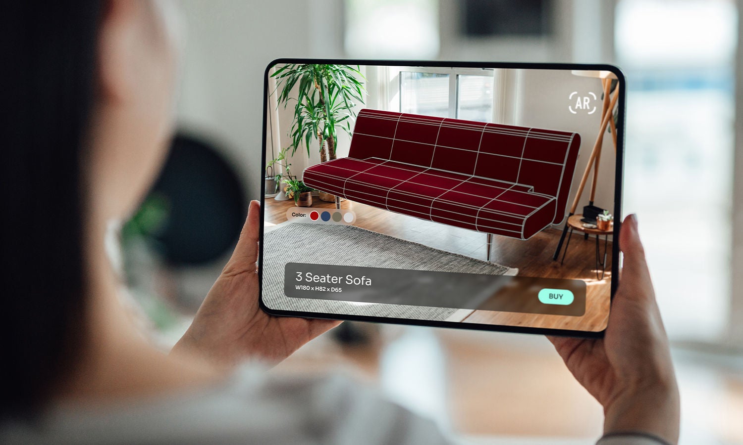 A woman viewing a couch on a tablet device.