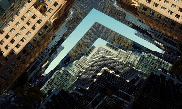 Aerial view of high-rise buildings forming an L-shaped gap and sharp skyline, highlighting urban density and geometry.
