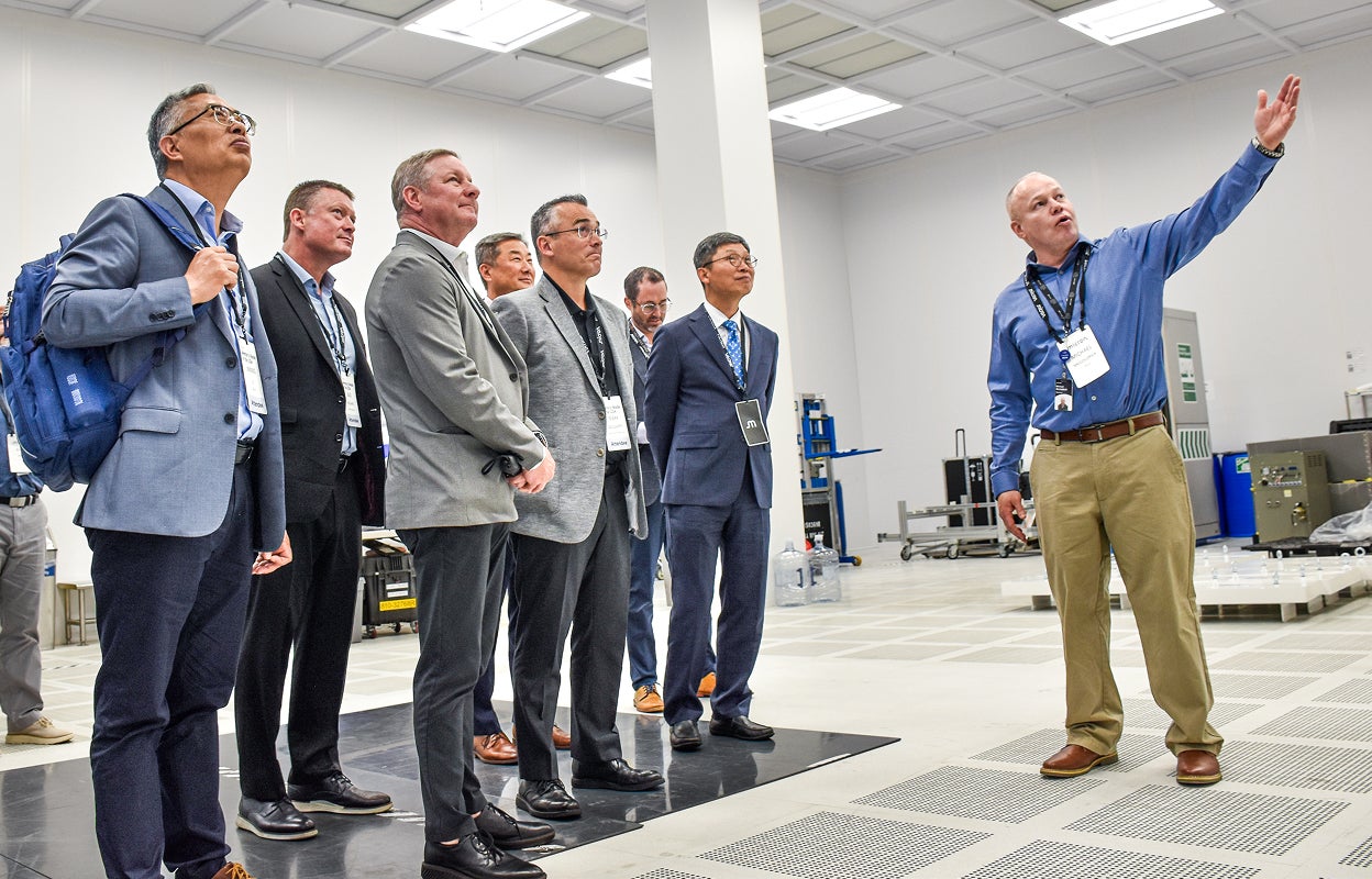 Visitors touring a technology facility and viewing equipment demonstrations.