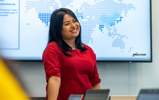 Woman smiles while presenting slides to an audience
