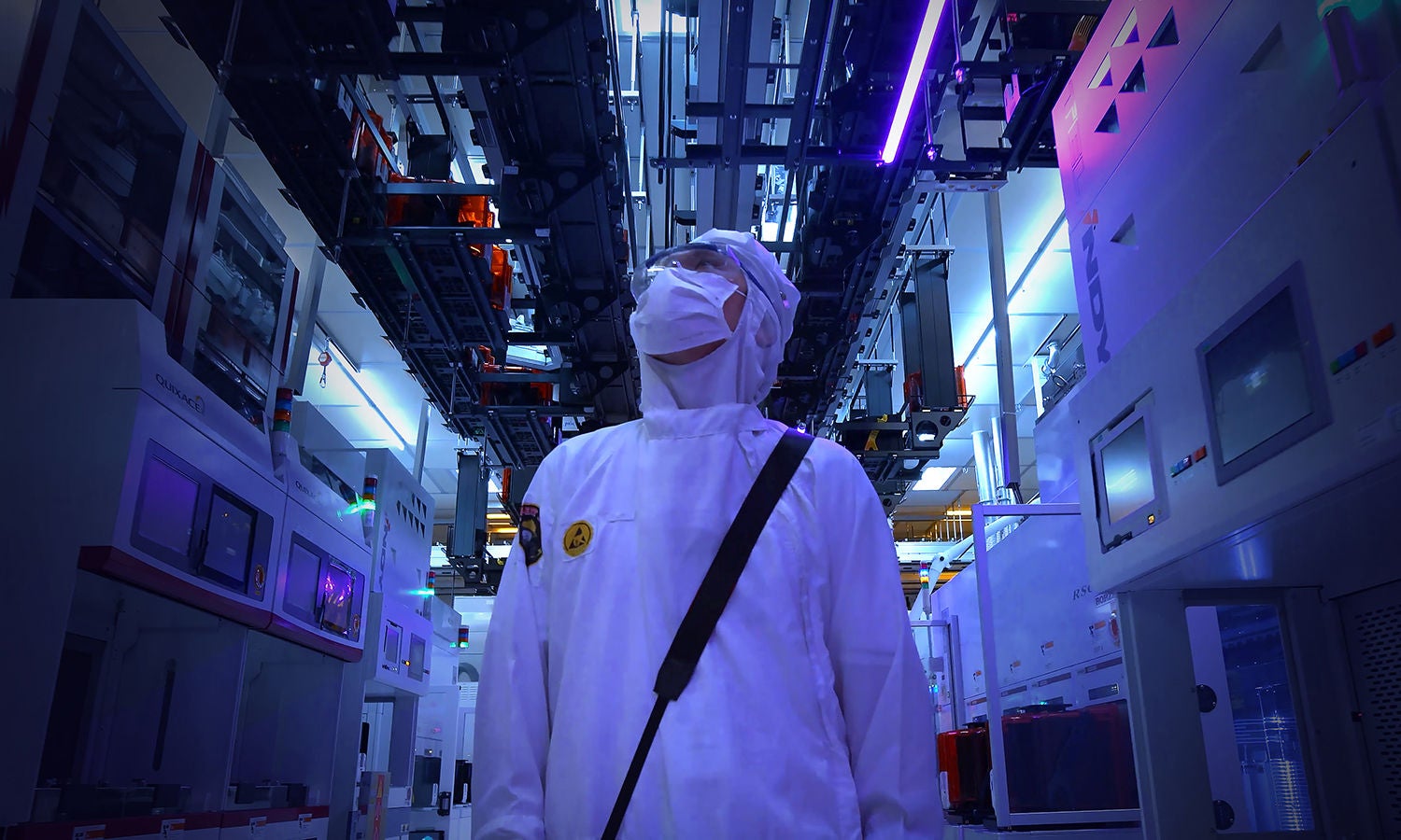 Worker in cleanroom suite observing equipment