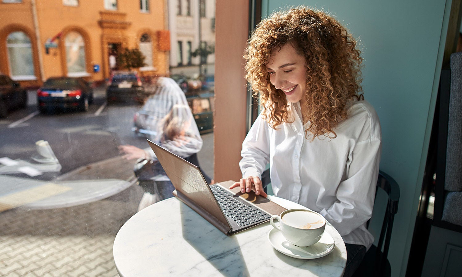 Woman in coffee shop working on ultra-portable laptop​