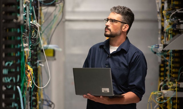 A Micron employee inspecting server wiring in a data center.