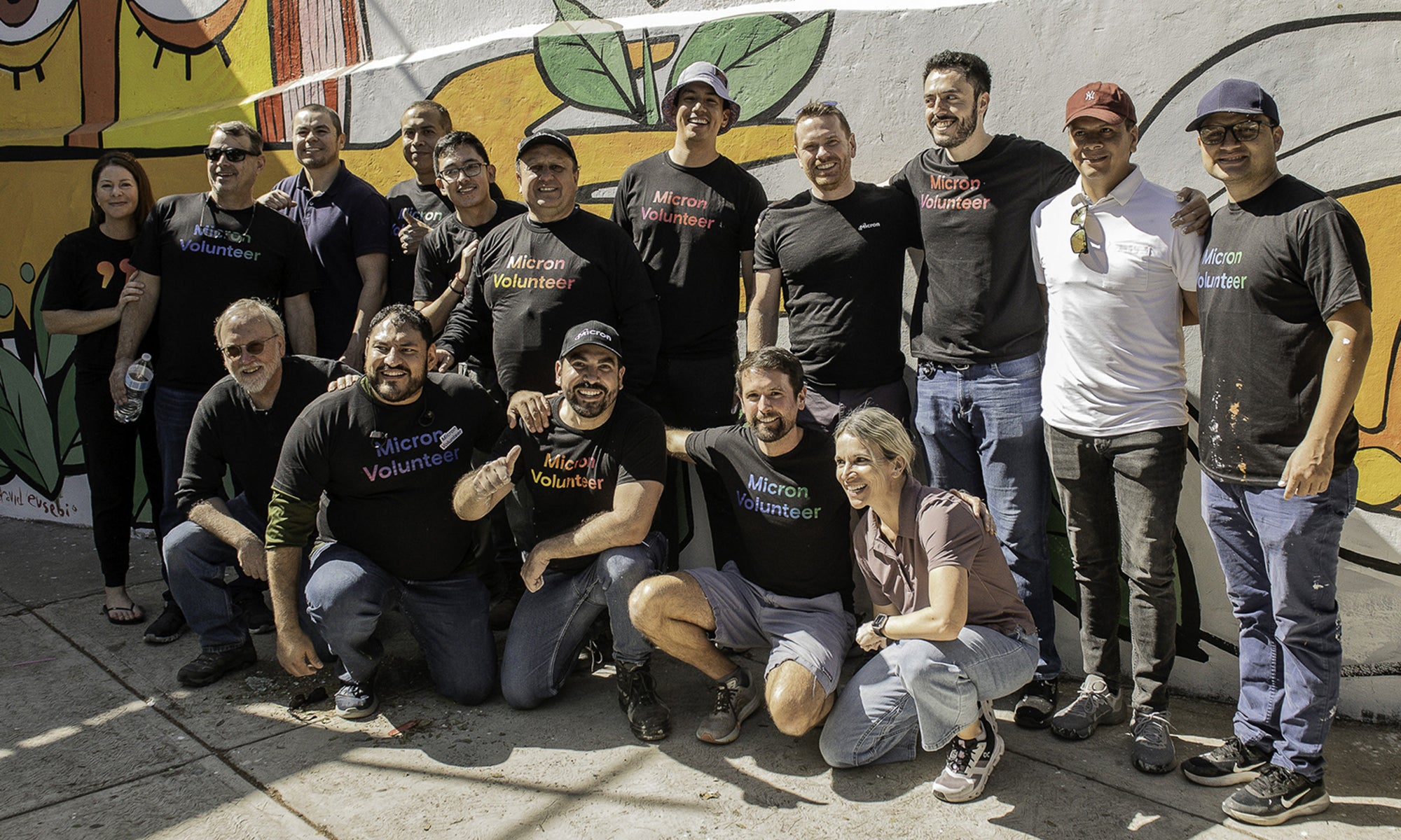 Micron volunteers posing for a group photo in front of a mural