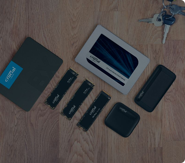 Various Crucial storage devices (SATA SSD, external SSDs,NVMe M.2 SSDs) neatly arranged and spaced out on a wood surface next to a set of car keys.