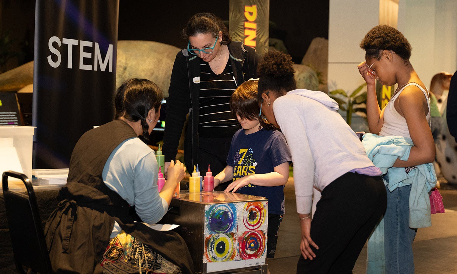 Children and adults participating in a hands-on STEM activity at a Micron exhibit.