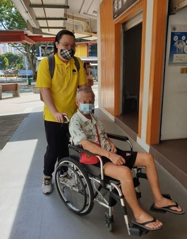 alt=“Jordon Ong 在 Seniors Befriending 提供志愿服务，为一位男性推轮椅”