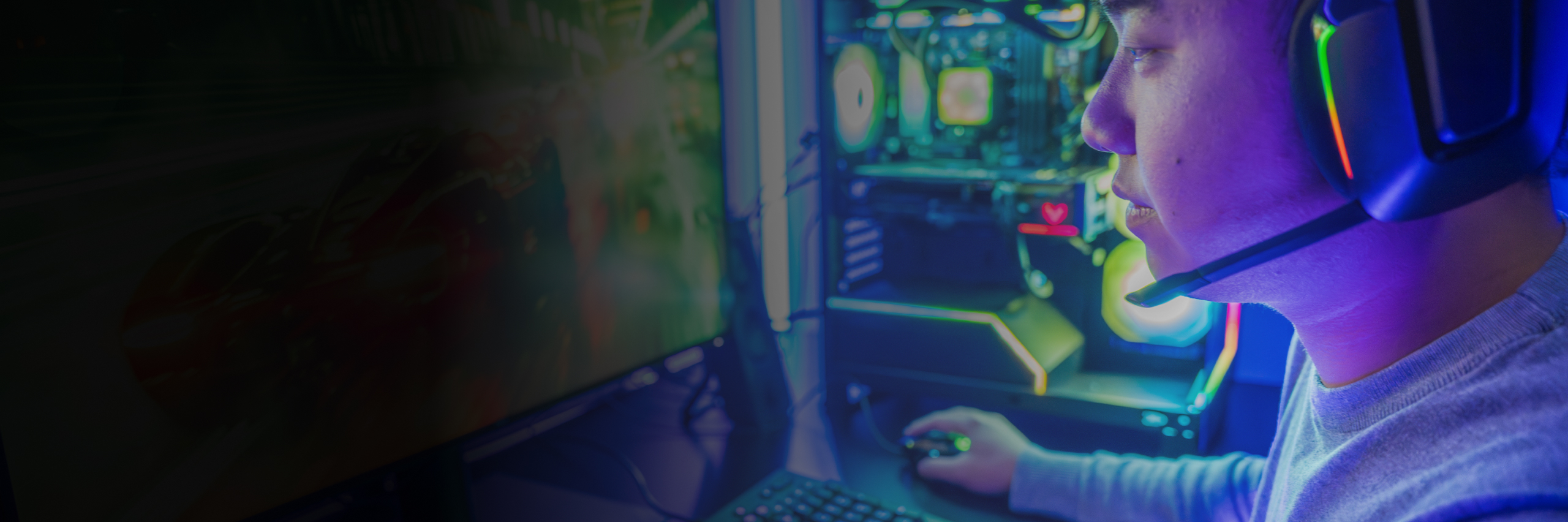 Gamer looking at PC screen with PC tower in background with lights