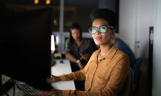 Woman in a dark office working at her computer