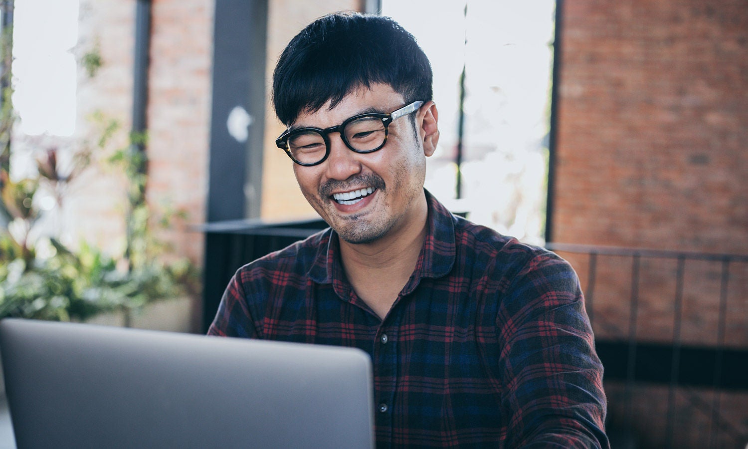 Person wearing glasses using a laptop indoors