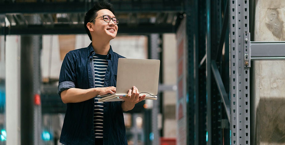 Man holding laptop in warehouse