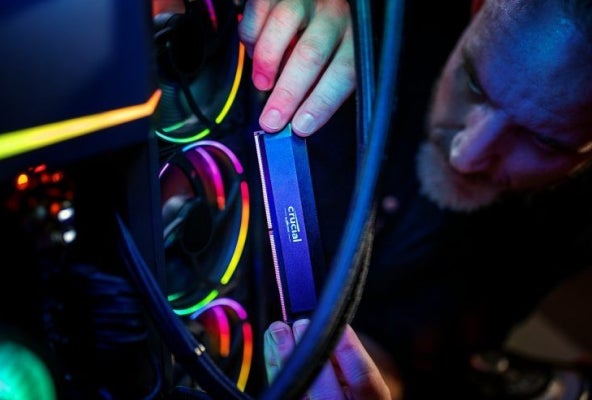 A Crucial DDR5 Pro installed into a RGB gaming PC in dark room.