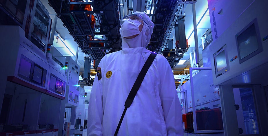 身穿洁净服的智能工厂工程师正在检查设备