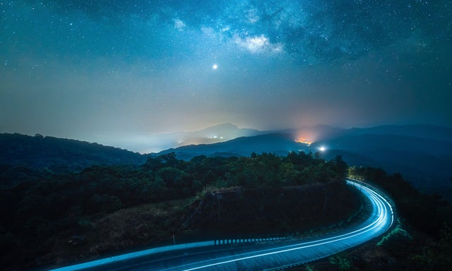 Night sky with mountain road with car light