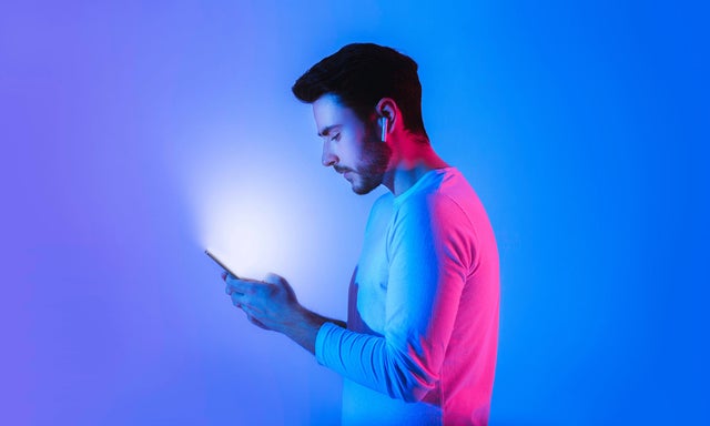 Side-view of a man typing on a mobile device with a blue background
