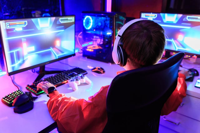 ヘッドホンをつけ、ビデオゲームをする少年