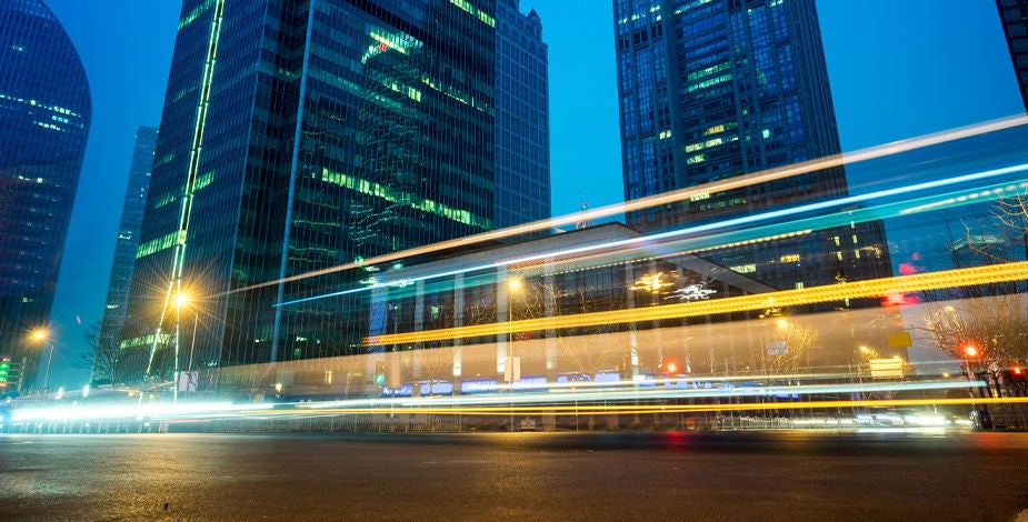 A city skyline at dusk with a time-lapsed traffic overlay