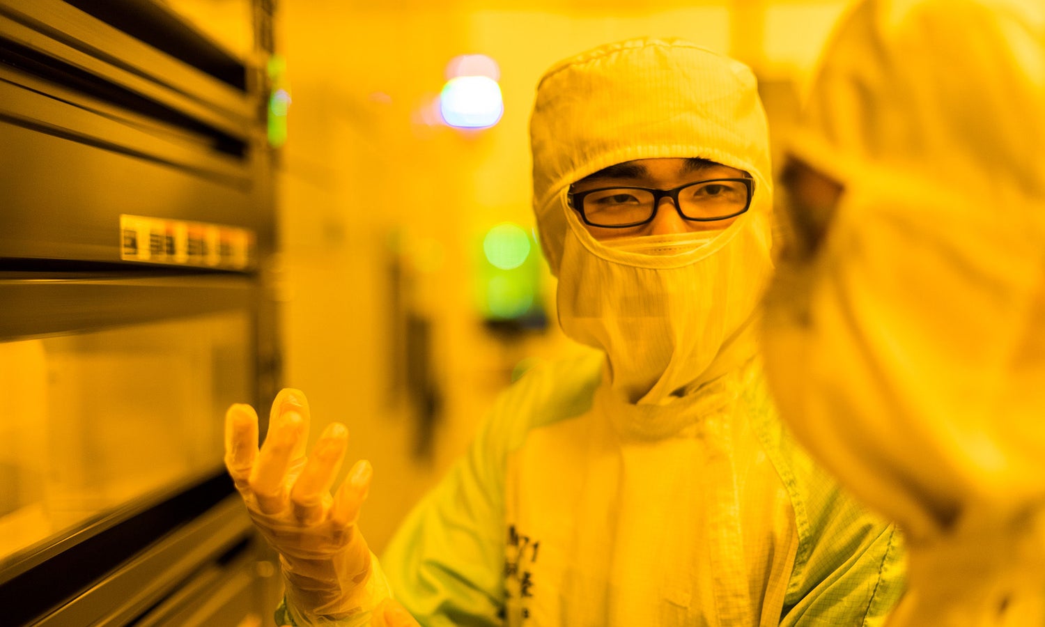 Bunny suited co-workers discussing  a project in a lab setting