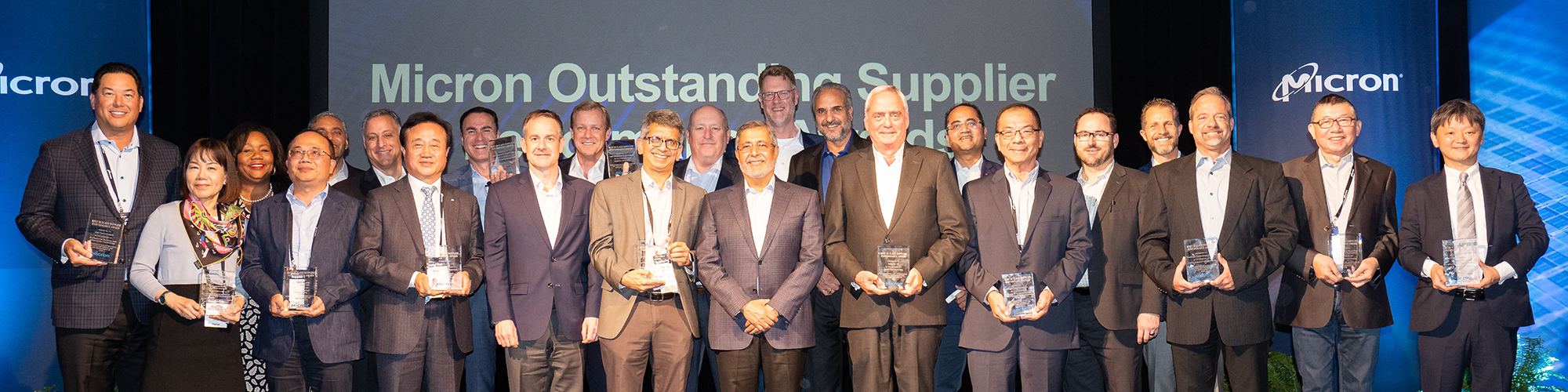 Group of Micron employees posing with an award along with the CEO at the center