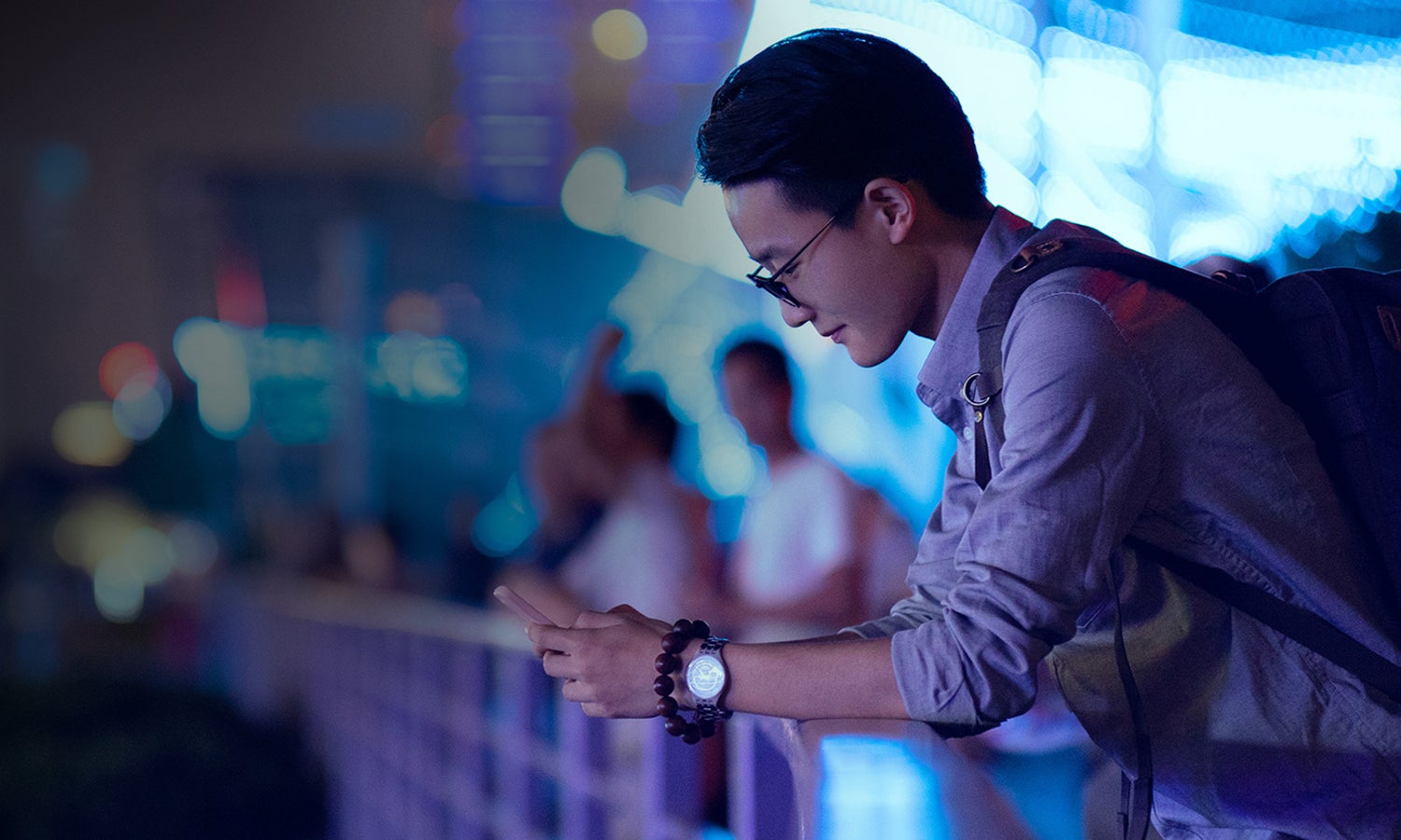 A businessman leaning over a rail, using a mobile device.