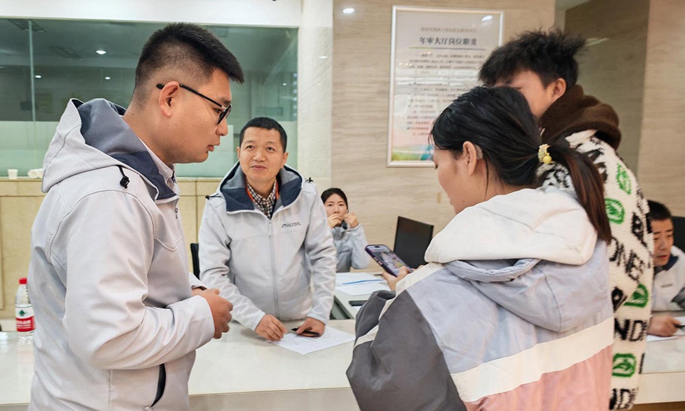People standing at an indoor reception counter reviewing papers together